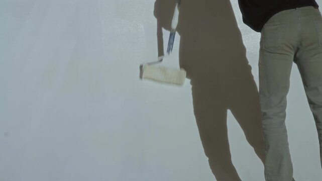 An employee paints a cyclorama in a photo studio with white paint
