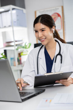 Female doctor laptop stethoscope office clinic vertical professional asian consultation Confident female doctor white coat with stethoscope using laptop for online consultation bright clinic