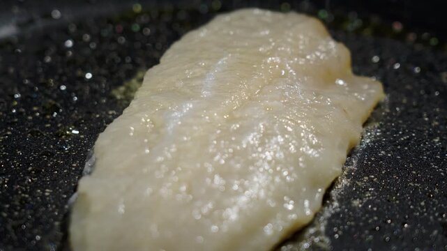 Frying white fish fillets. Frying hake fillets in a hot pan Opaque cod fillet turning tender in pan, gentle simmering, flesh loosening into flakes, soft sheen and subtle browning,