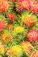 Fototapeta premium Fresh Rambutan Fruit Background with Vibrant Red and Green Spiky Texture, for Tropical Food Packaging, Exotic Market Ads, Healthy Nutrition Content, and Summer Harvest Concepts