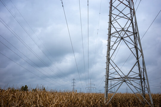 High-voltage power pylons against a cloudy sky. Distribution of electrical power via an overhead wire line.