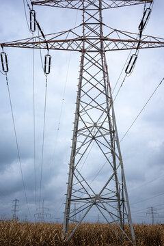 High-voltage power pylons against a cloudy sky. Distribution of electrical power via an overhead wire line.