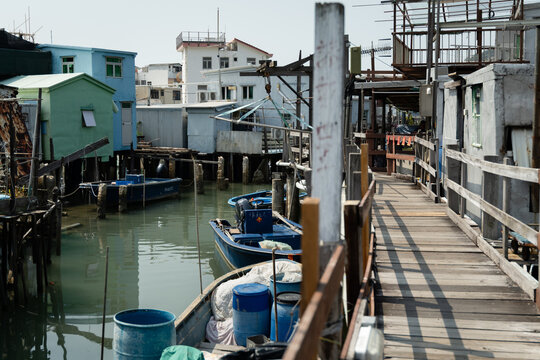 Weathered wooden boardwalk and railing between Pang Uk stilt houses at Tai O fishing village on Lantau Island, Hong Kong, on a clear sunny day