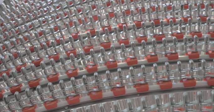 A multi-tiered spiral conveyor in operation, stainless steel mesh belts are moving. A working transport system with an axisless spiral. Close-up handheld indoors shot, real time speed.