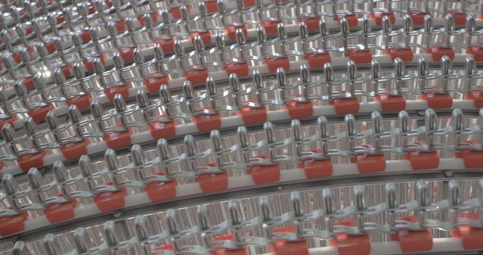 A multi-tiered spiral conveyor in operation, stainless steel mesh belts are moving. A working transport system with an axisless spiral. Close-up handheld indoors shot, real time speed.
