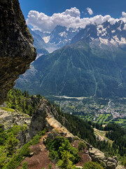 Expansive view from from La Flégére a mountain ridge revealing the Chamonix valley with a town nestled below and the snow-capped mont blanc mountain range dominating the dramatic alpine landscape.