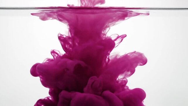 Abstract purple ink dissolving in water creating dynamic flowing forms