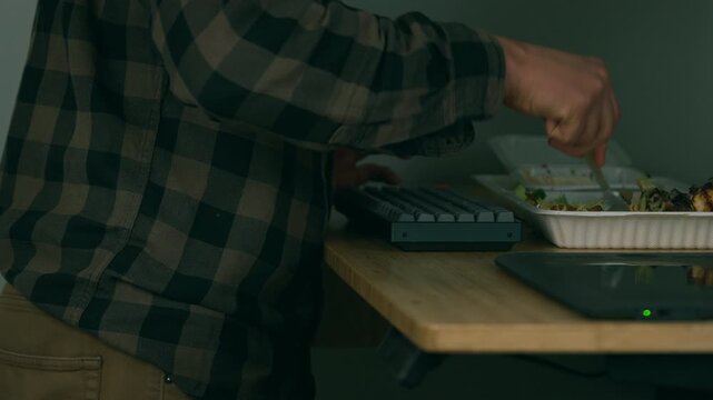 Man eating takeaway food while working at his desk