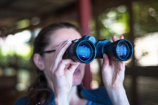 Young woman looking through binoculars, perfect exploration concept. Very shallow focus.