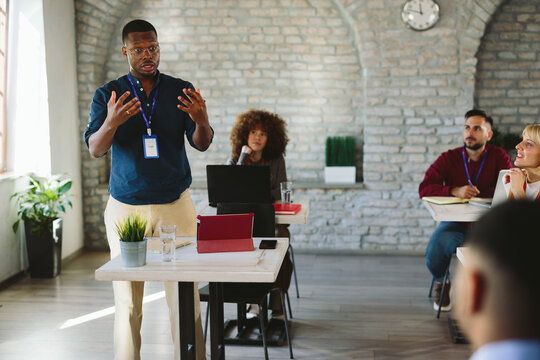 Black businessman facilitating meeting and discussing ideas with diverse team