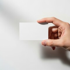 Obraz premium A hand holding a small blank white square against a plain background