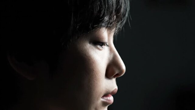 Close-up Profile of Young Man's Face with Dramatic Lighting, Contemplative Mood