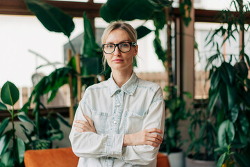 Mid aged business woman standing in a modern office and looking at the camera.
