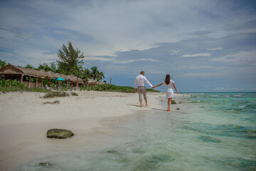 Obraz premium Couple walking barefoot on tropical beach