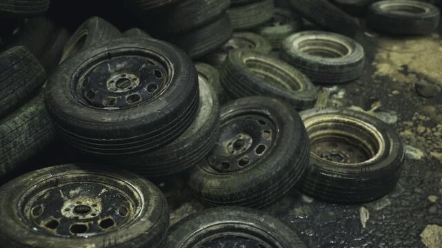 Tires by workshop. Wet tire stack shines with oil and rusted metal. Damp tires beside workshop with shimmering puddles and aged metal surfaces