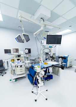 Wide view of fully equipped modern hospital operating room. Spacious surgical theater with anesthesia machine, c-arm x-ray and operating table.