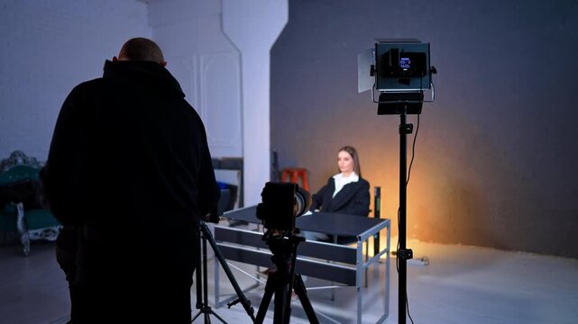 Studio footage of a blog. Cameras and soffits are directed on the woman in black jacket sitting at desk.