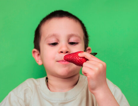 Boy About to Bite into Strawberry with Eyes Half Closed and Slight Smile &mdash; Child Savouring Fresh Summer Fruit, Mindful Eating, Sensory Pleasure and Healthy Food Concept