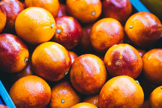 Vibrant close-up of fresh organic blood oranges in a crate. The ripe citrus fruits show beautiful red and orange textured peels, perfect for healthy food concepts, juice marketing, and agriculture.