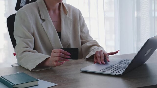 A happy businesswoman uses a bank card to transfer money to her account via her computer and the internet.
A modern way to pay for goods.
Online shopping and a convenient way to pay into a bank accoun