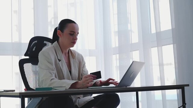 A woman makes digital purchases using a laptop and credit card.
Modern online shopping without going to the store.
Saving time on shopping trips.
Online shopping