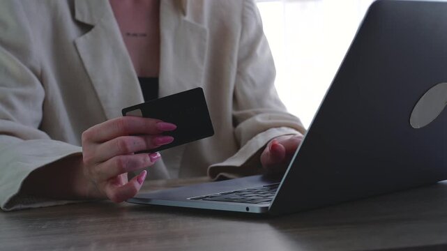 A woman makes digital purchases using a laptop and credit card.
Modern online shopping without going to the store.
Saving time on shopping trips.
Online shopping
