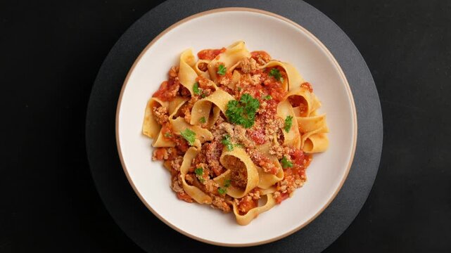 pappardelle pasta with Ground meat and tomato,spaghetti with a meat based bolognese tomatoes,served on white plate with parmesan cheese.Top view.
