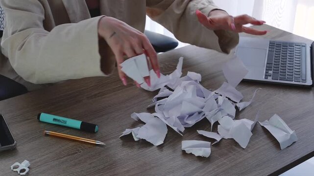 A messy desk.
A lot of paper trash on the office desk.
A girl tosses paper up while sitting at a desk in a bright office.
Problems at work.
Redoing work done.
