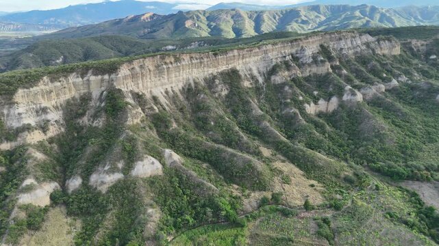 Drone shot of a steep mountain cliff showing soil stratification and lush vegetation