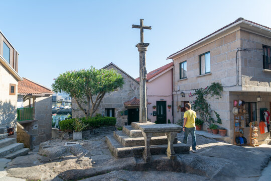 Traditional stone cruceiro cross located in a village square in Combarro, Galicia, Spain. Typical Galician architecture with stone houses and cultural heritage in a coastal historic town.