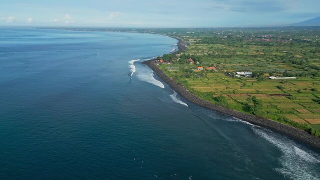 Wide aerial bay panorama with calm surf, green hinterland and distant volcanic silhouettes sweeping drone footage for tourism campaigns, coastal conservation visuals and serene,Bali island,Indonesia