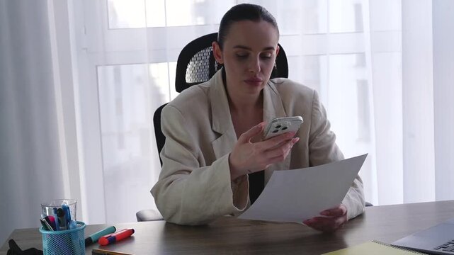 A businesswoman scans paper documents while sitting in an office.
A woman with a mobile phone takes a photo of documents.
Electronic documents.
QR code on a white sheet of paper.
