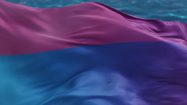 Bisexual pride flag waving in wind over blue water, LGBTQ identity and equality concept