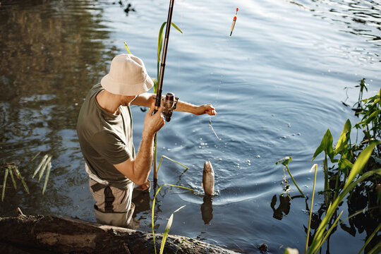 Young fisherman with fishing rod near the lake at summer