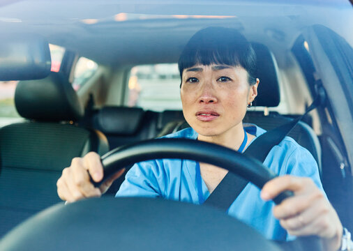 Female nurse sitting in car, going home from work. Female doctor driving car to work, on-call duty.