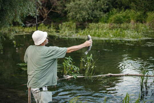 Fisherman with fishing rod near the lake at summer