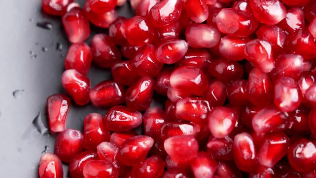Ceramic dish with wet pomegranate seeds. Bright red arils with water droplets. Healthy food concept