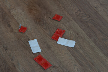 Scattered condom packets on a floor with red and white packaging