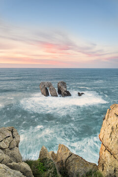 Urro del Manzano rock formation in Liencres at sunset with long exposure silk effect on the ocean