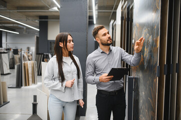 Seller assisting female customer choosing large tiles