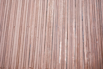 Fototapeta premium Faded reddish brown vertical wooden slats securely fastened with tiny metal nails creating a repetitive architectural wall cladding texture full of vintage rustic character