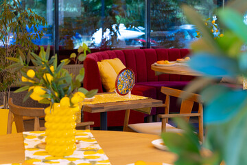 Cozy restaurant interior with red booth and wooden tables decorated with lemons and plants