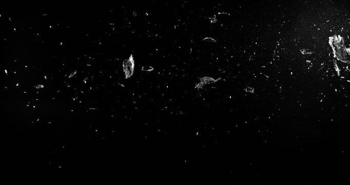 Super slow motion shattering glass filmed at 1000fps, side view with flying shards and dust isolated on black background. Perfect VFX overlay element for impact, crash or transition.