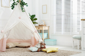 Toy wigwam with pillows, furniture and floral decor in room, space for text © New Africa