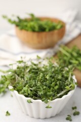 Fototapeta premium Fresh microgreens in bowl on white table, closeup