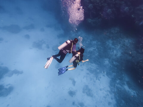 Undersea view of a certified instructor training a young woman student how to scuba dive in the Red Sea Egypt