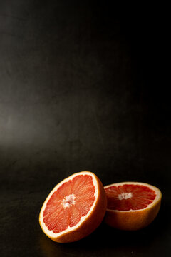 Grapefruit cut in half on a dark surface 