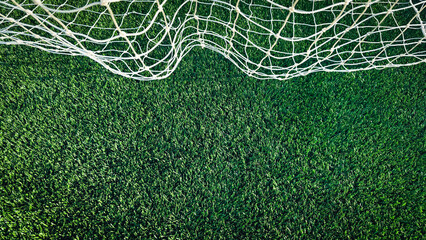 Overhead banner sized view of a white soccer goal net on vibrant, newly installed synthetic green turf. A crisp, high-contrast background for sports and athletic themes. © Sanya Kushak