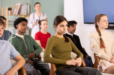 Fototapeta premium Attentive teenage students listening to lecture while female doctor stands in blurred background