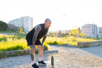 Tattooed man resting after intensive outdoor workout
